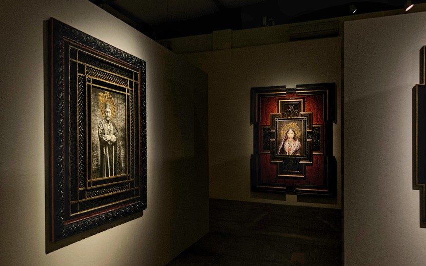 A couple of large frames of portraits hung on walls perpendicular to each other in a gallery