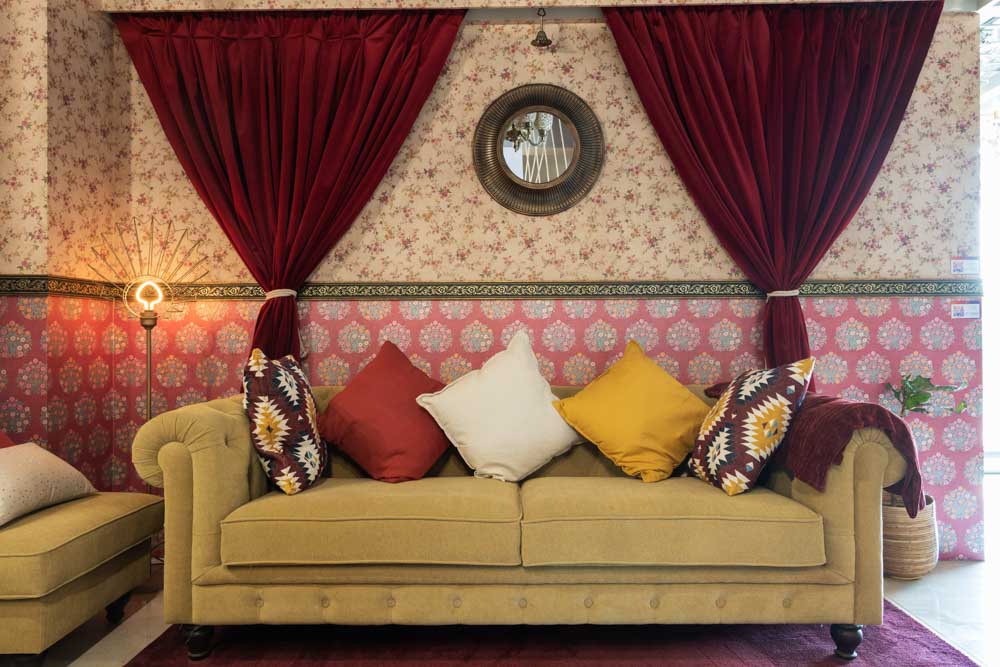 A wallpapered Living room with a yellow sofa and red curtains