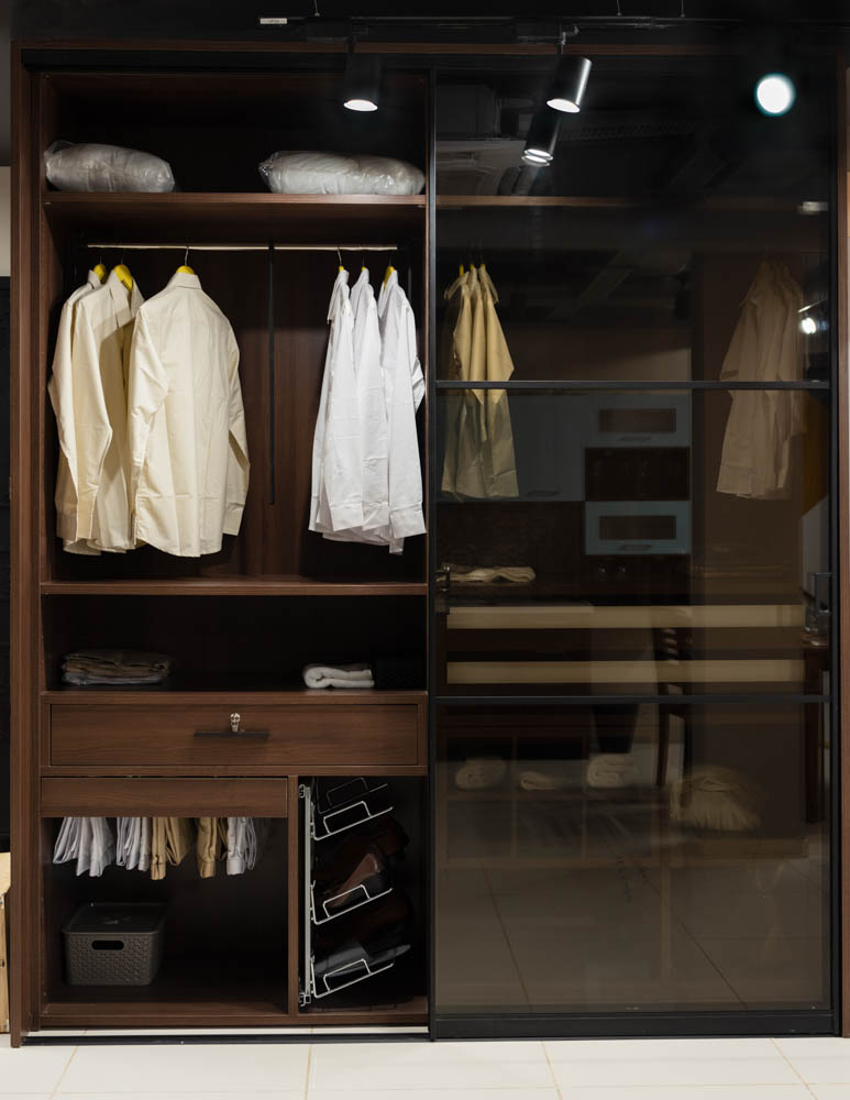 A closet with glass doors and clothes hung inside it
