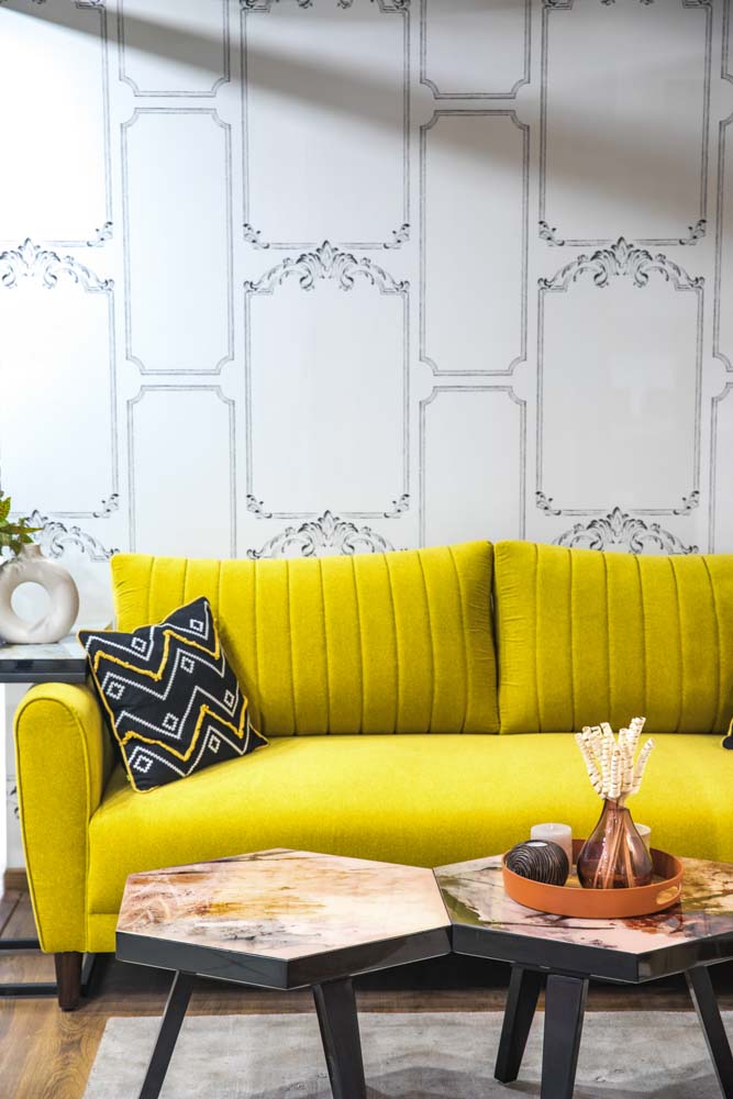 A yellow sofa placed in front of a wallpapered wall