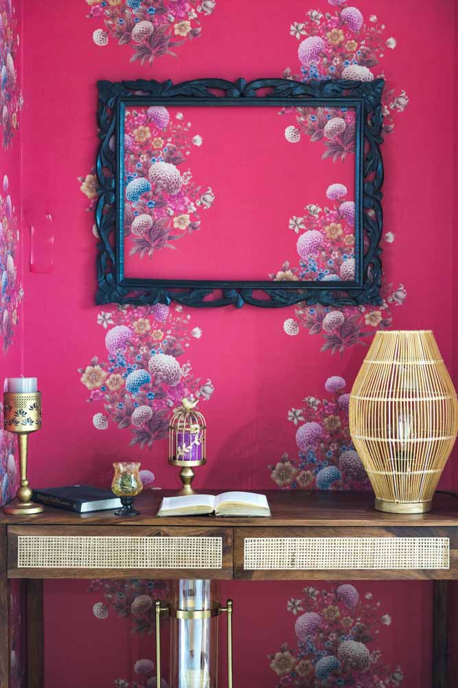  A pink floral wallpaper with a rattan console places in front of it