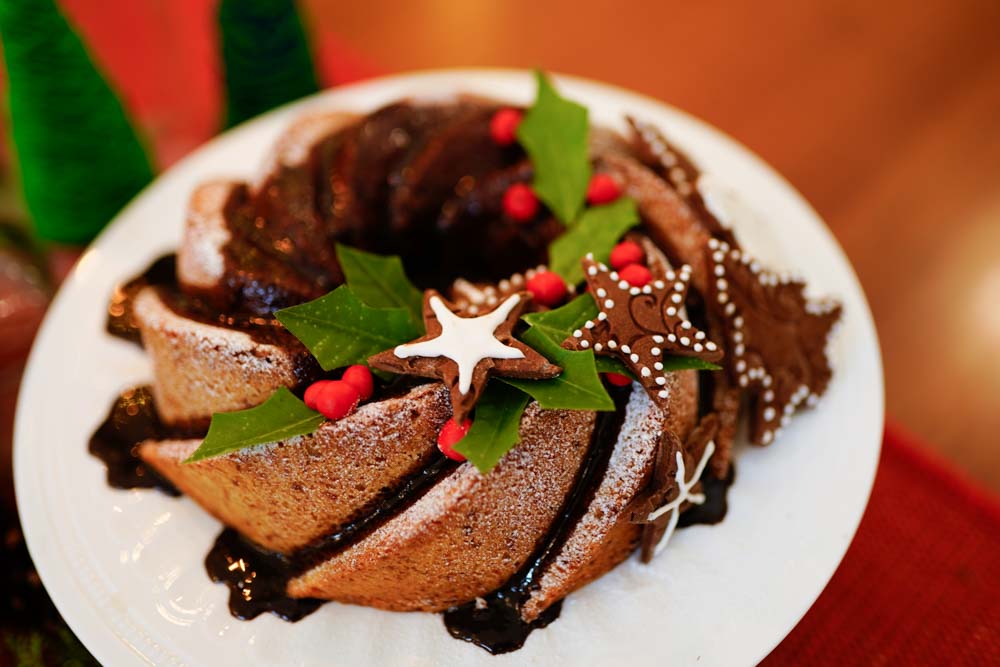 A christmas pound cake in a white plate decorated with leaves and cookies