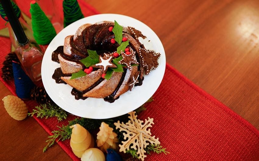 A christmas pound cake on a white plate placed on a wooden table with a red table runner