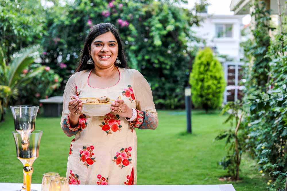 Chef Neha Mathur holding a bowl full of Chicken Malai curry