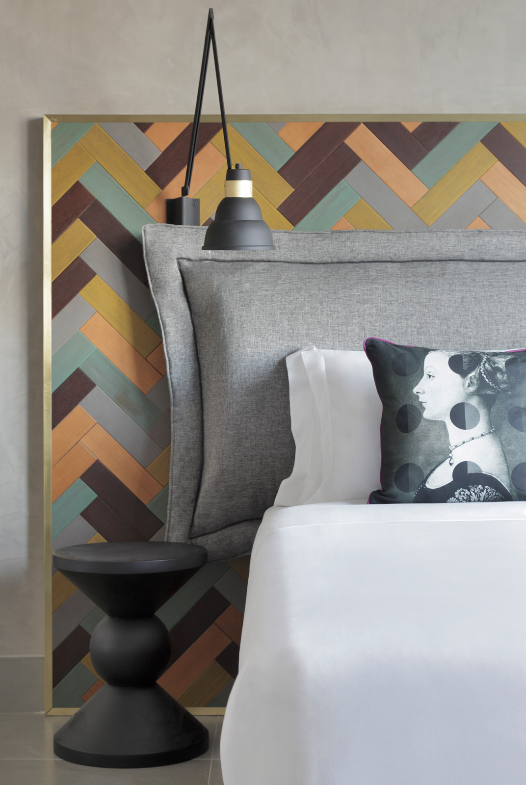 A colourful headboard stands out against the otherwise monochromatic walls and bed linen - Beautiful Homes