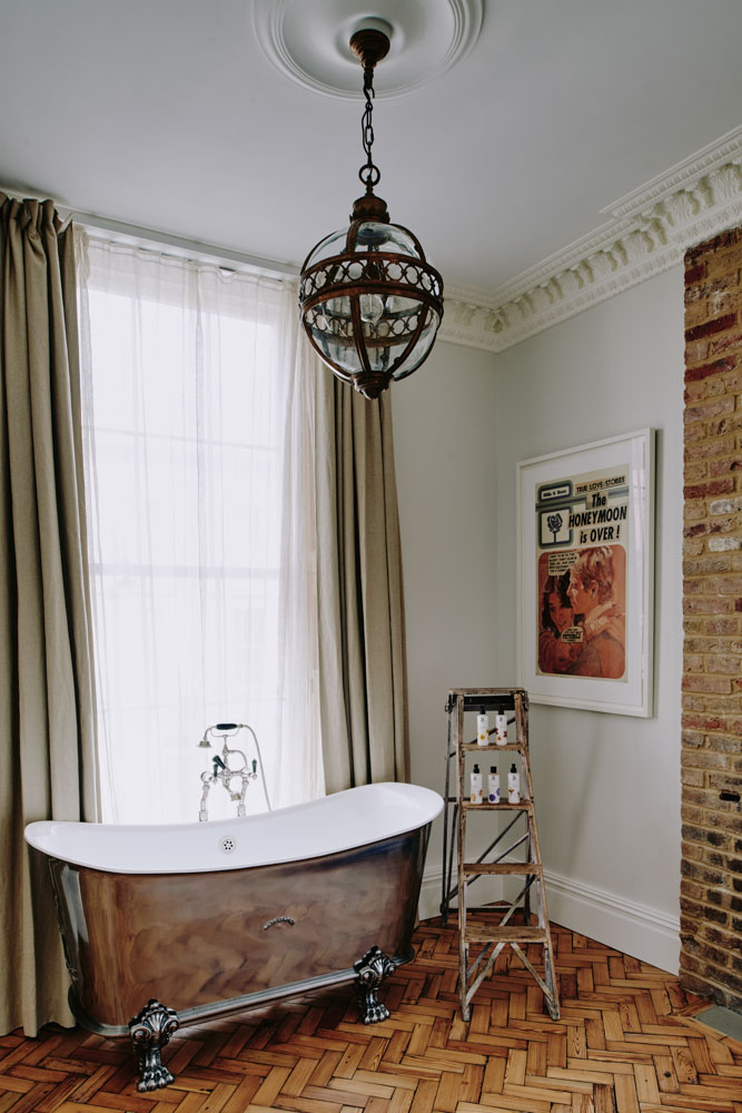Bathroom with repurposed ladder as shelves, next to vintage bathtub with metallic coating