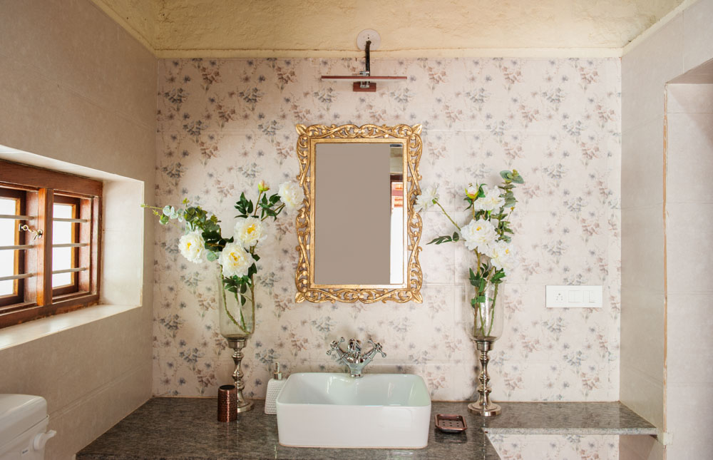 Low-ceiling loft bathroom with Victorian wallpaper and mirror frame with flower arrangements