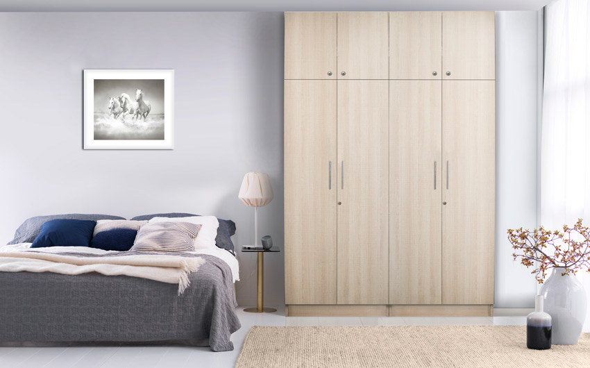 A bedroom with a wardrobe, bed, rug and artwork