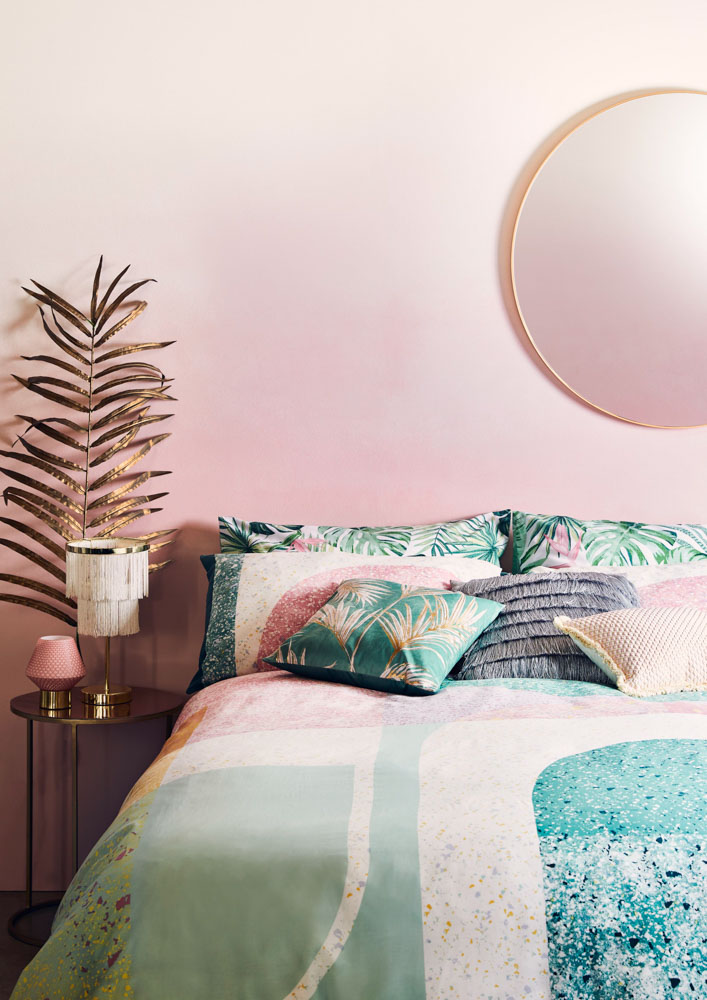 Bedroom Design with Tropical Prints in Pink and Sea Green Shades and Golden-Rimmed Round Mirror Design - Beautiful Homes