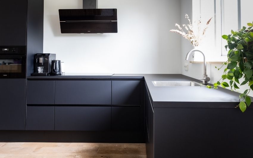 All black L-shaped modular kitchen design with wooden flooring - Beautiful Homes
