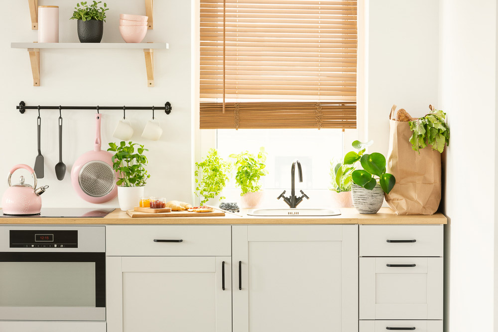 Simple kitchen design in light pink, several potted plants and hanging kitchen décor tools - Beautiful Homes