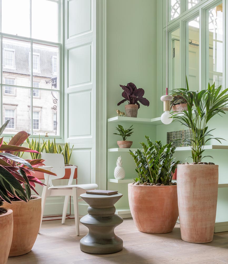 Pastel Green Living Room With a Grey Stool & a Naked Bulb Pendant Lamp - Beautiful Homes