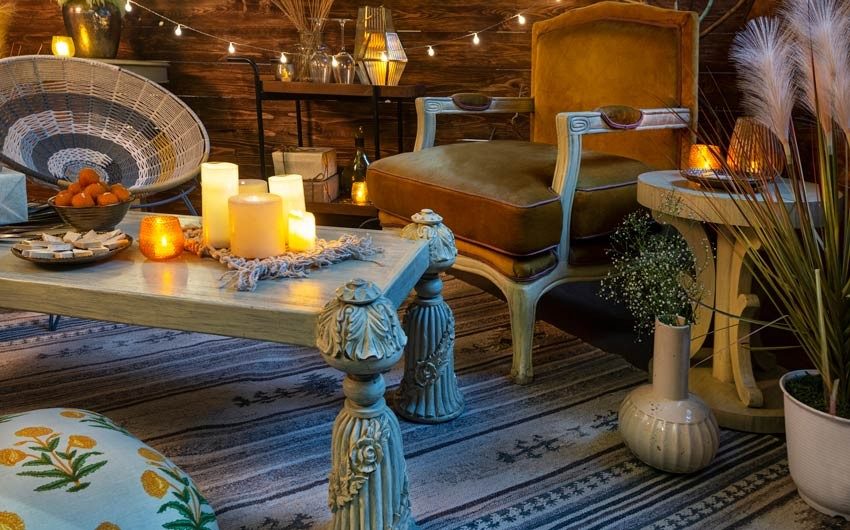 A white coffee table placed on a white and blue rug, a wooden chair with a vase and a side table placed next to it