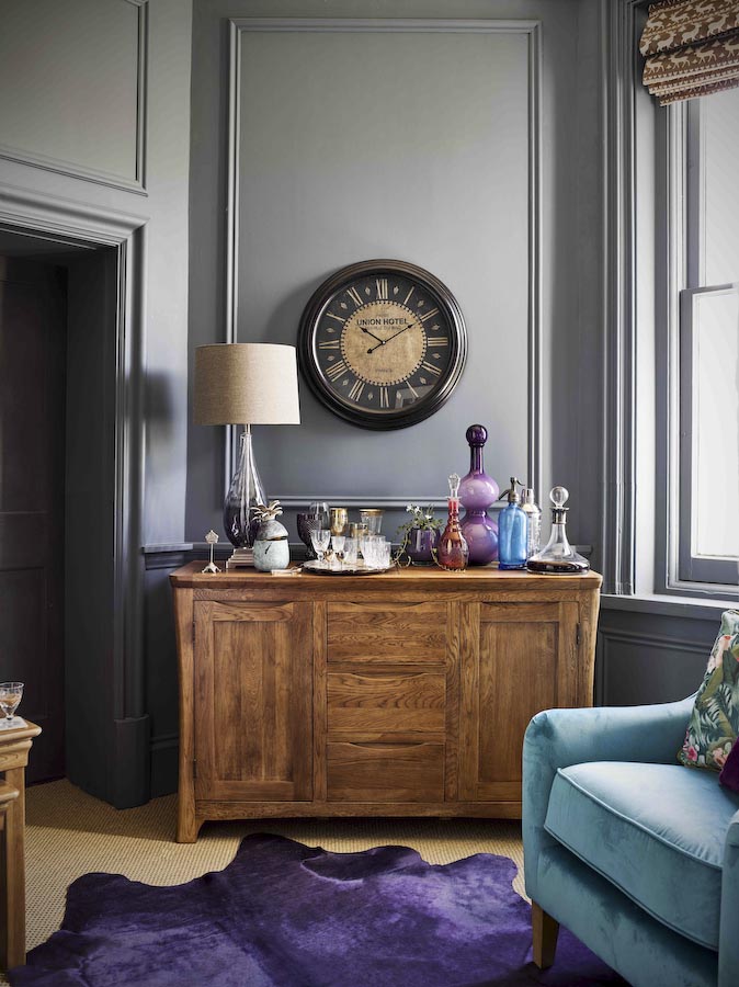 Wooden Home Bar Design With Rusty Vibe Consisting Of Velvet Rug & Sofa, Antique Side Table & Clock - Beautiful Homes