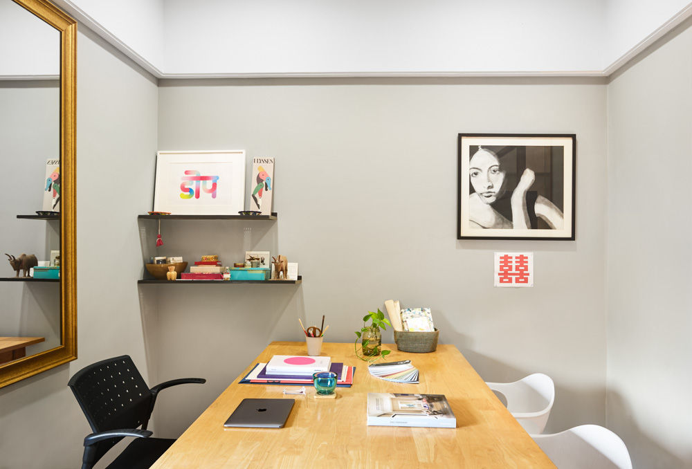 Office cabin of designer Ritu nanda with a wooden desk, a golden framed mirror, a painting of a lady on one wall and an artwork which has 'dope' written in hindi - Beautiful Homes