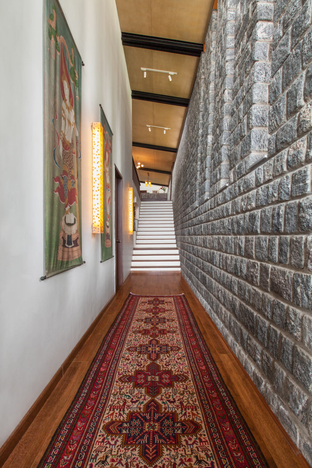 A brightly patterned rug and a wall decorated with all the artworks at entryway - Beautiful Homes